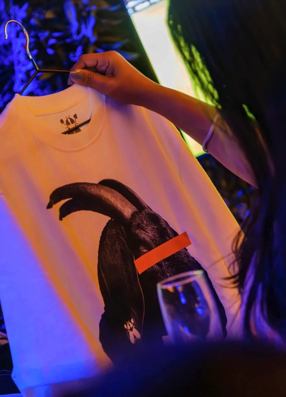 The SACXESS IMBUZI tee held up on a hanger under evening light